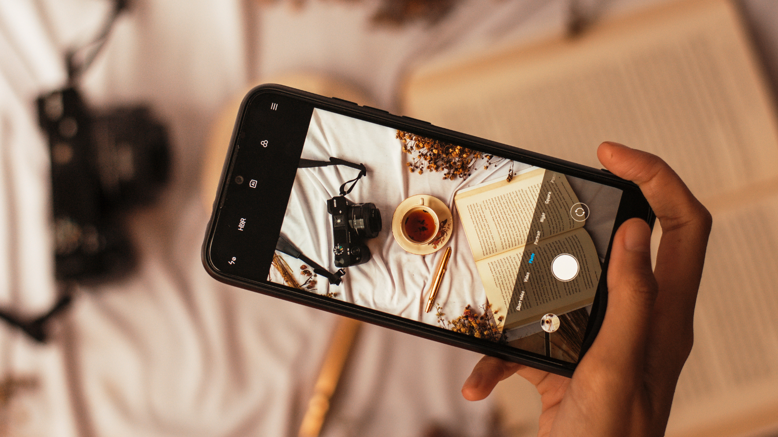 smartfon robi zdjęcie książki, kawy i aparatu na instagrama