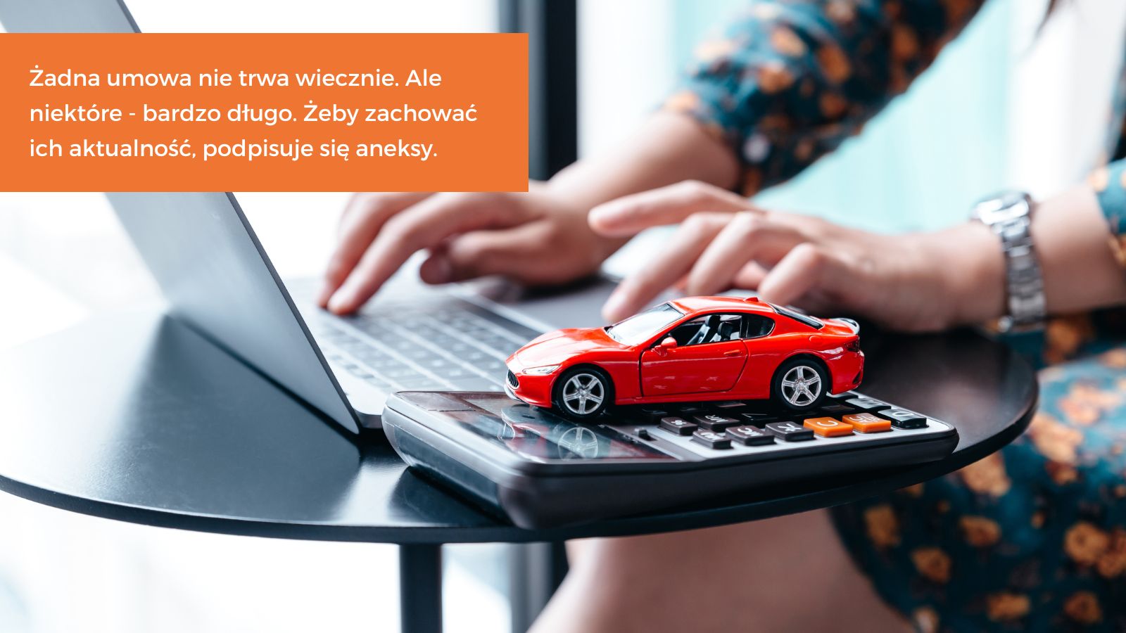Ręce kobiety na klawiaturze laptopa, obok leży kalkulator, na którym stoi miniaturowy samochód zabawka